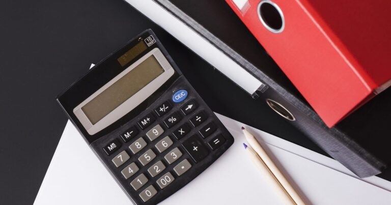 Cost of HR outsourcing shown by a calculator and paperwork on a desk